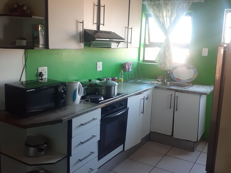 A functional kitchen featuring built-in cabinetry, laminate countertops, a built-in oven with extractor fan, and tiled flooring.
