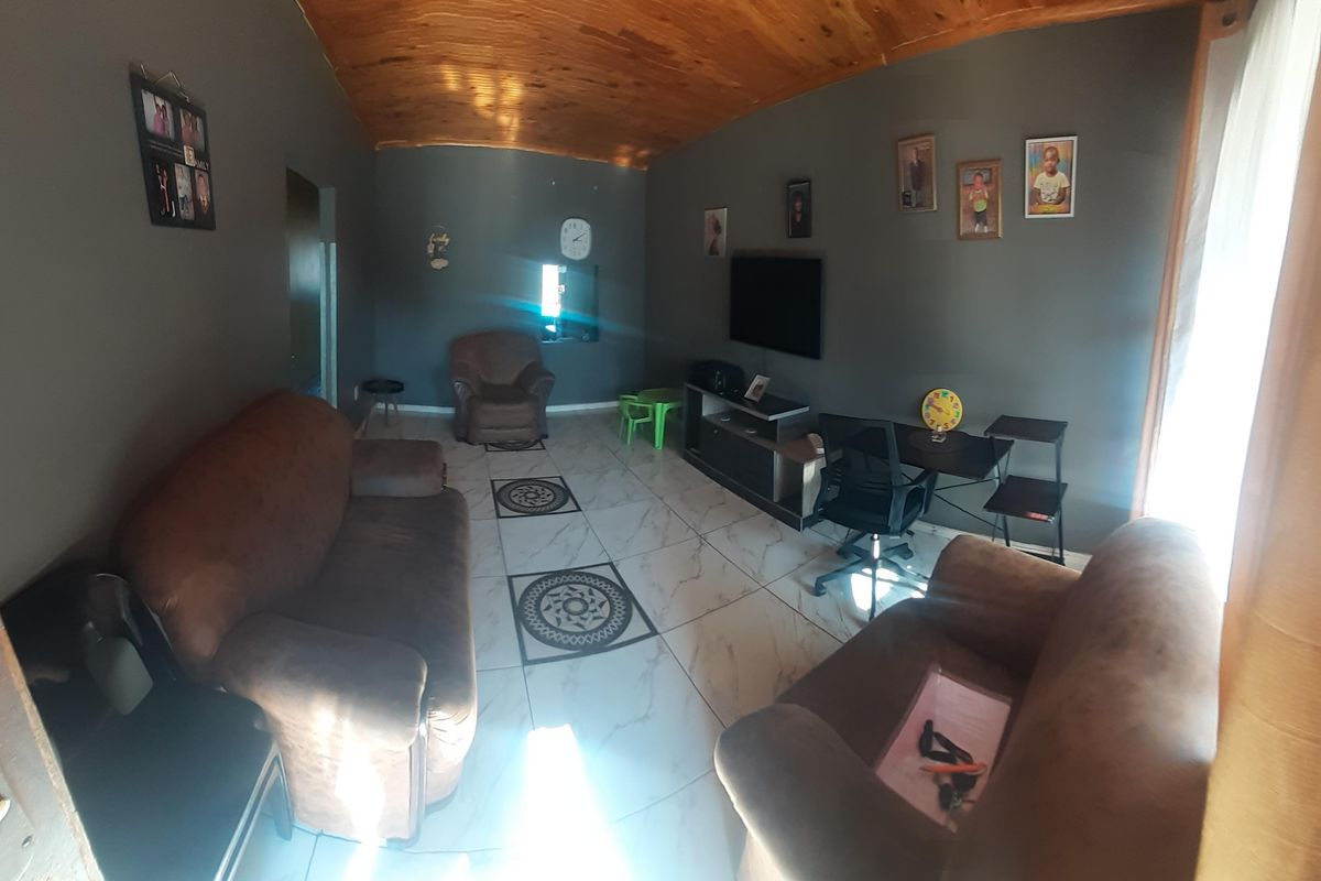 A living room featuring a vaulted timber ceiling and tiled flooring with decorative inlays, providing a functional and comfortable living space.