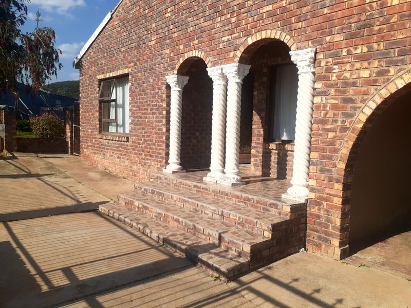 Front entrance of a face brick house featuring arched architectural details, decorative columns, and tiled steps leading to the main door.