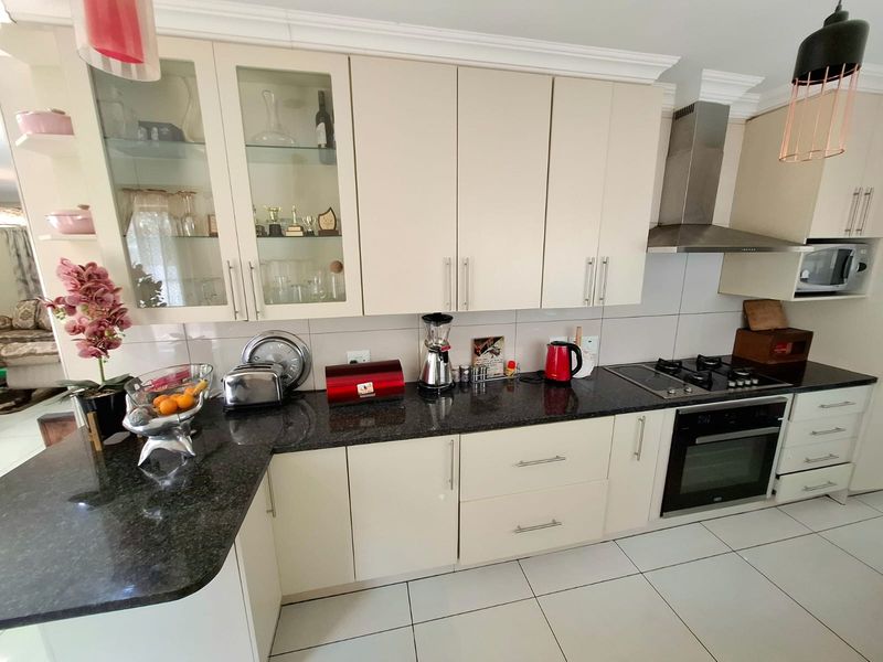 A well-maintained kitchen featuring cream cabinetry, dark granite countertops, stainless steel appliances, and tiled flooring, offering a functional and clean cooking space.