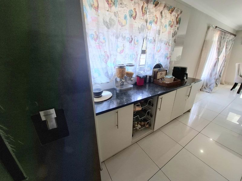 A functional kitchen area featuring modern white cabinetry, dark granite countertops, and polished floor tiles.