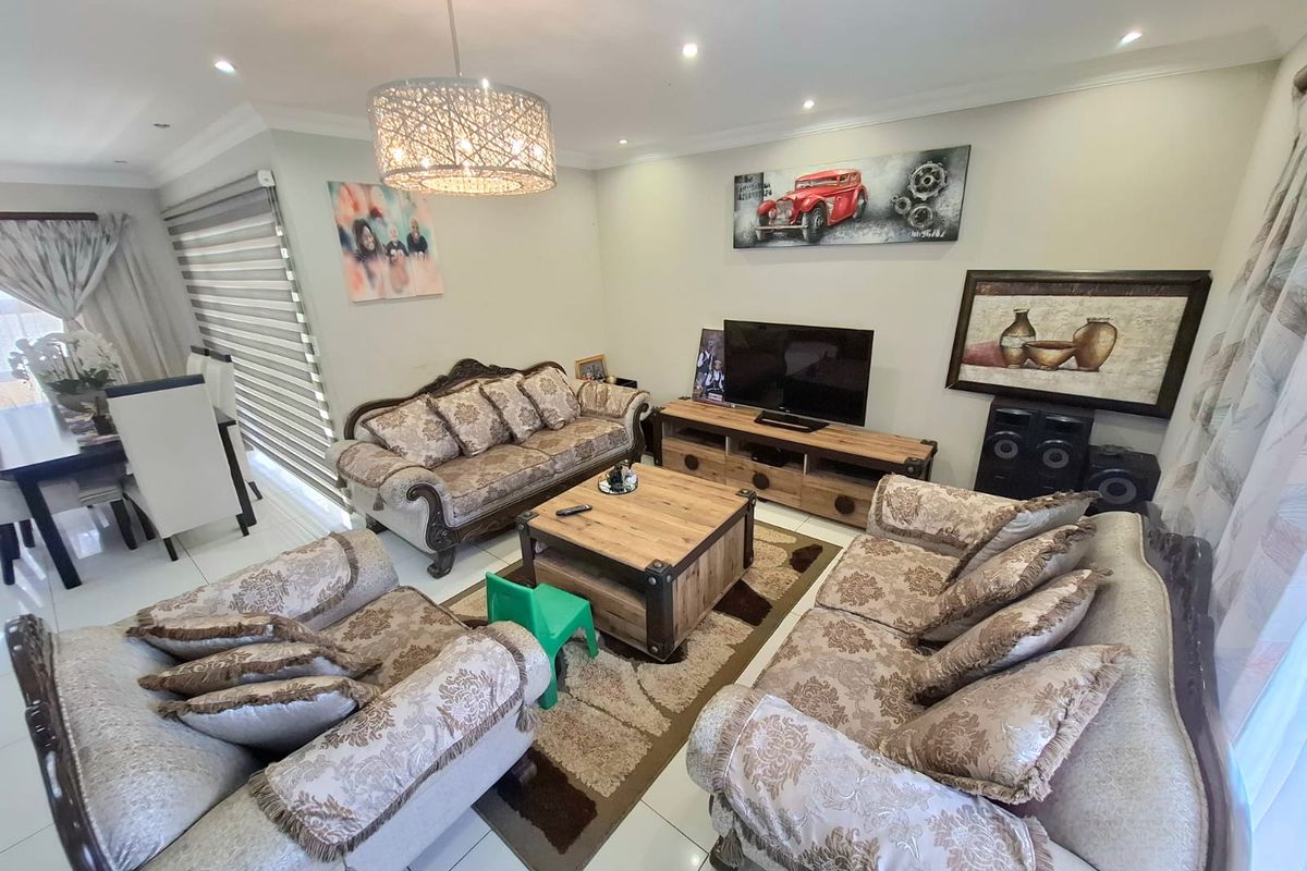 A well-lit living room featuring tiled flooring, recessed downlighting, and a decorative pendant light, creating a comfortable and functional space.