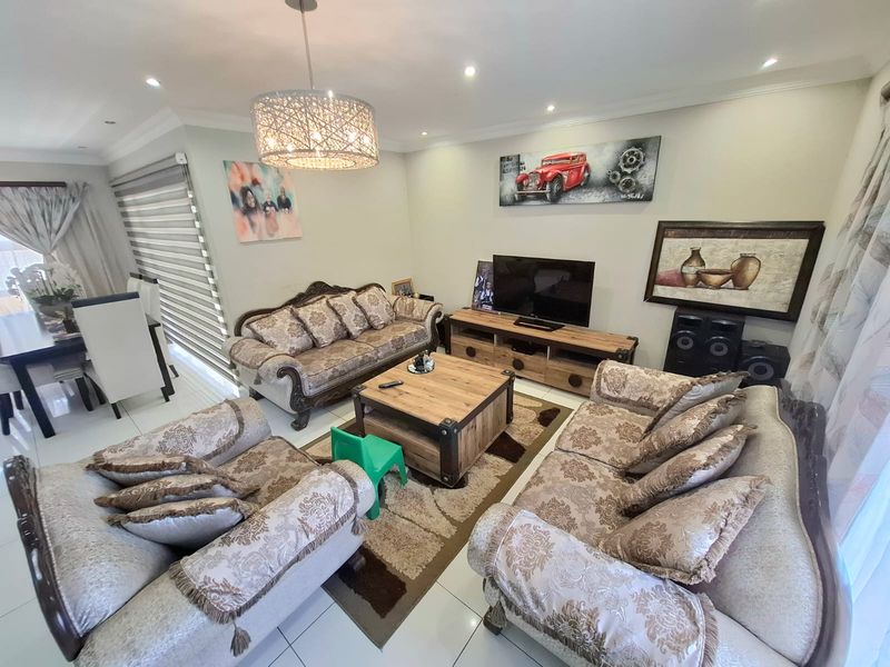A well-lit living room featuring tiled flooring, recessed downlighting, and a decorative pendant light, creating a comfortable and functional space.