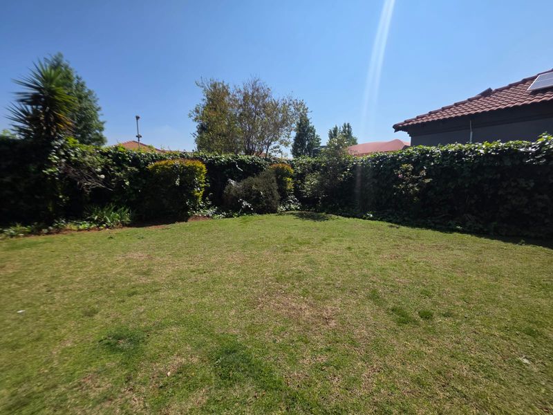 A private, well-established garden featuring a manicured lawn and mature perimeter hedging, providing a secluded outdoor space.