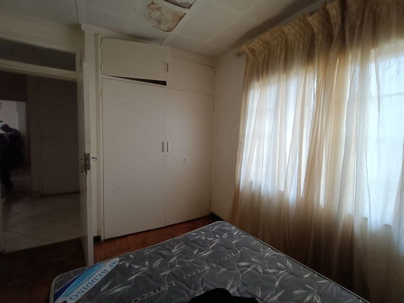 Bedroom featuring built-in cupboards and parquet flooring, requiring ceiling repairs due to visible water damage.