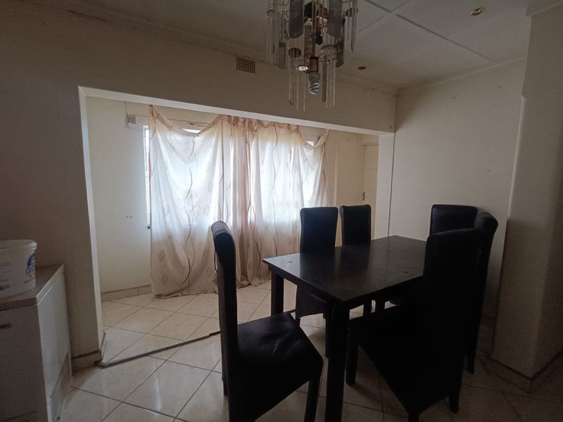 A dining area featuring tiled flooring and a central ceiling light fixture, requiring cosmetic updates to improve the overall aesthetic and finish.