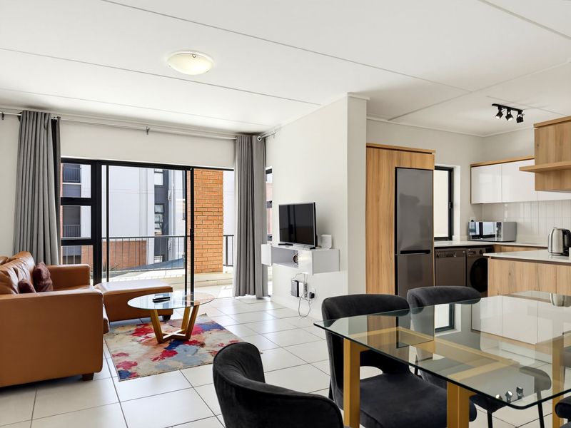 Modern open-plan living area featuring tiled floors, a contemporary kitchen with built-in cabinetry, and large sliding doors leading to a balcony.
