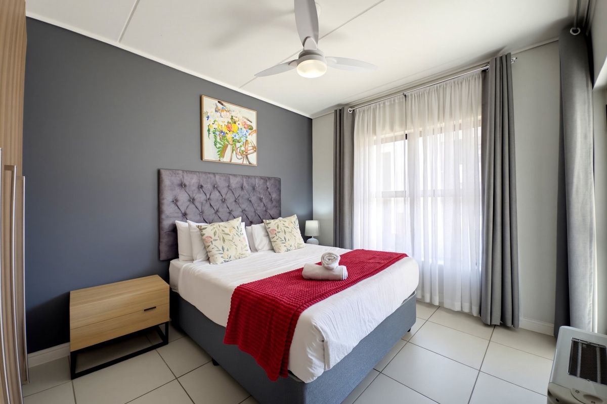 A well-maintained bedroom featuring tiled flooring, a ceiling fan, and a built-in wardrobe, offering a clean and comfortable living space.