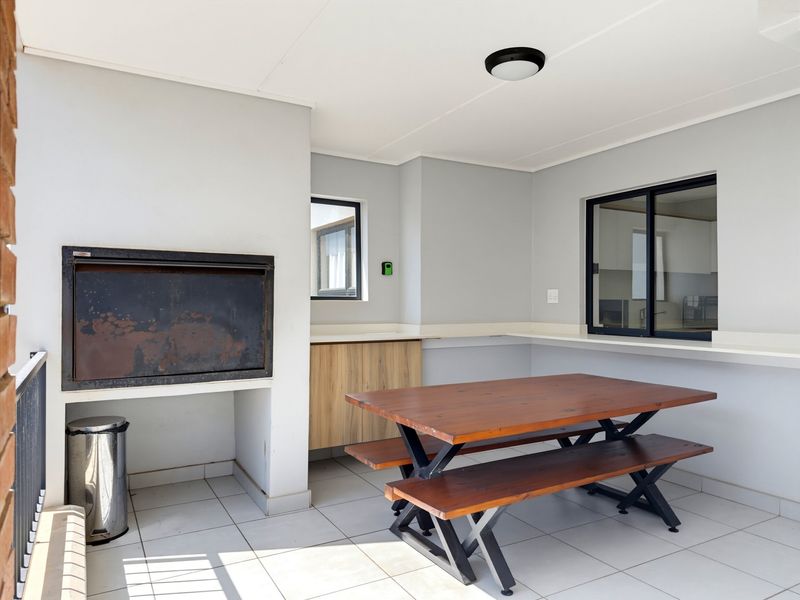 Covered patio area featuring a built-in braai, tiled flooring, and a convenient serving counter, ideal for outdoor dining and entertaining.