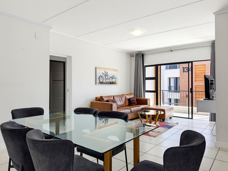 An open-plan living and dining area featuring tiled flooring and a large sliding glass door providing access to a private balcony.