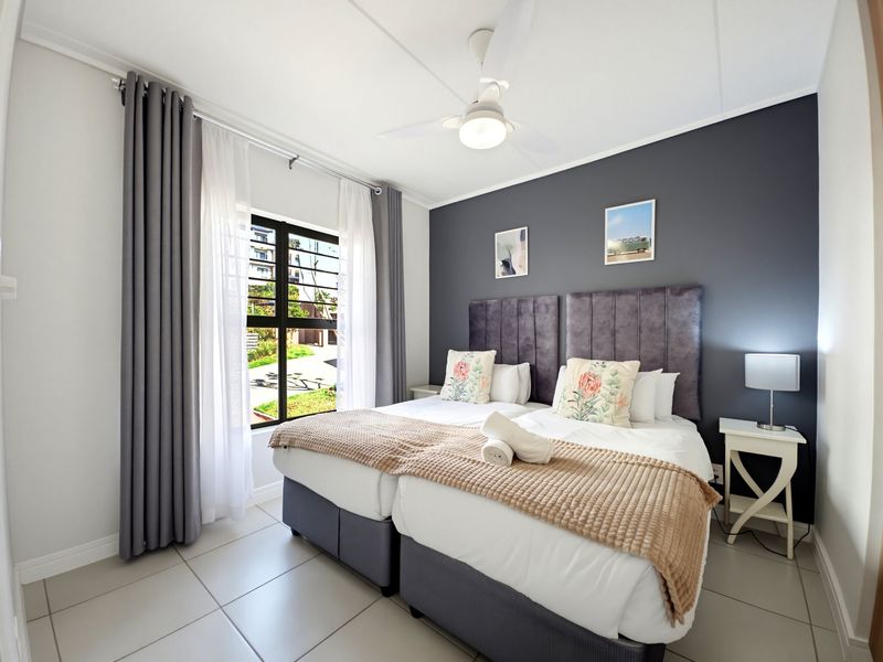A well-maintained bedroom featuring tiled flooring, a ceiling fan, and a large window with views of the exterior.