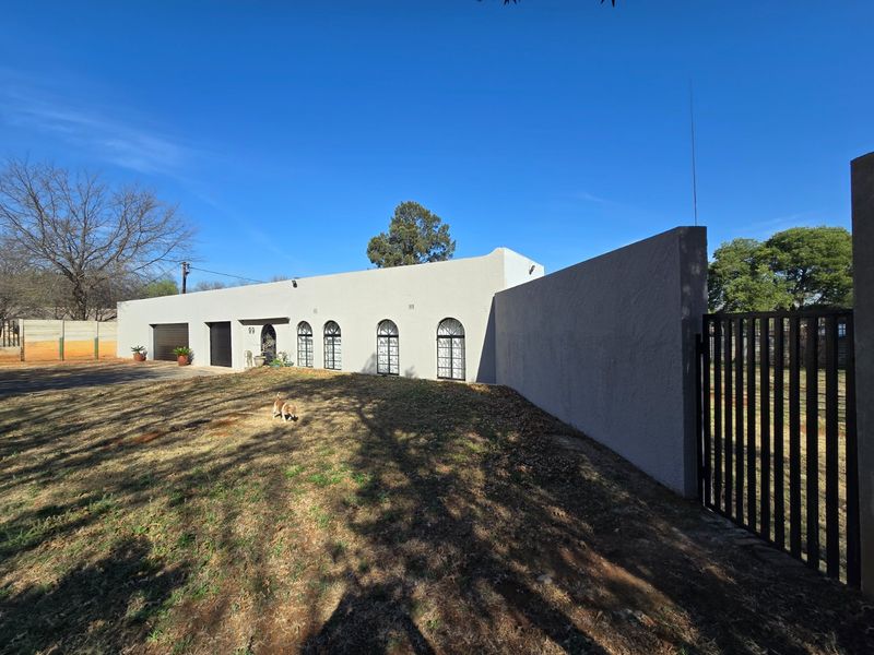 Front elevation of a single-story house featuring a stucco facade, arched windows, and a secure gated entrance with an attached garage.