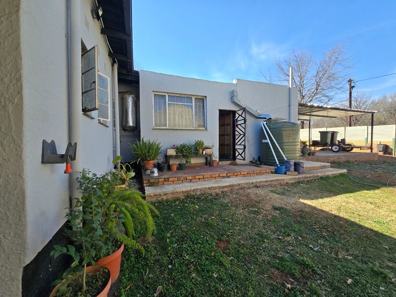 Rear exterior view of the property featuring a brick patio area, water tank, and security gate access to the home.