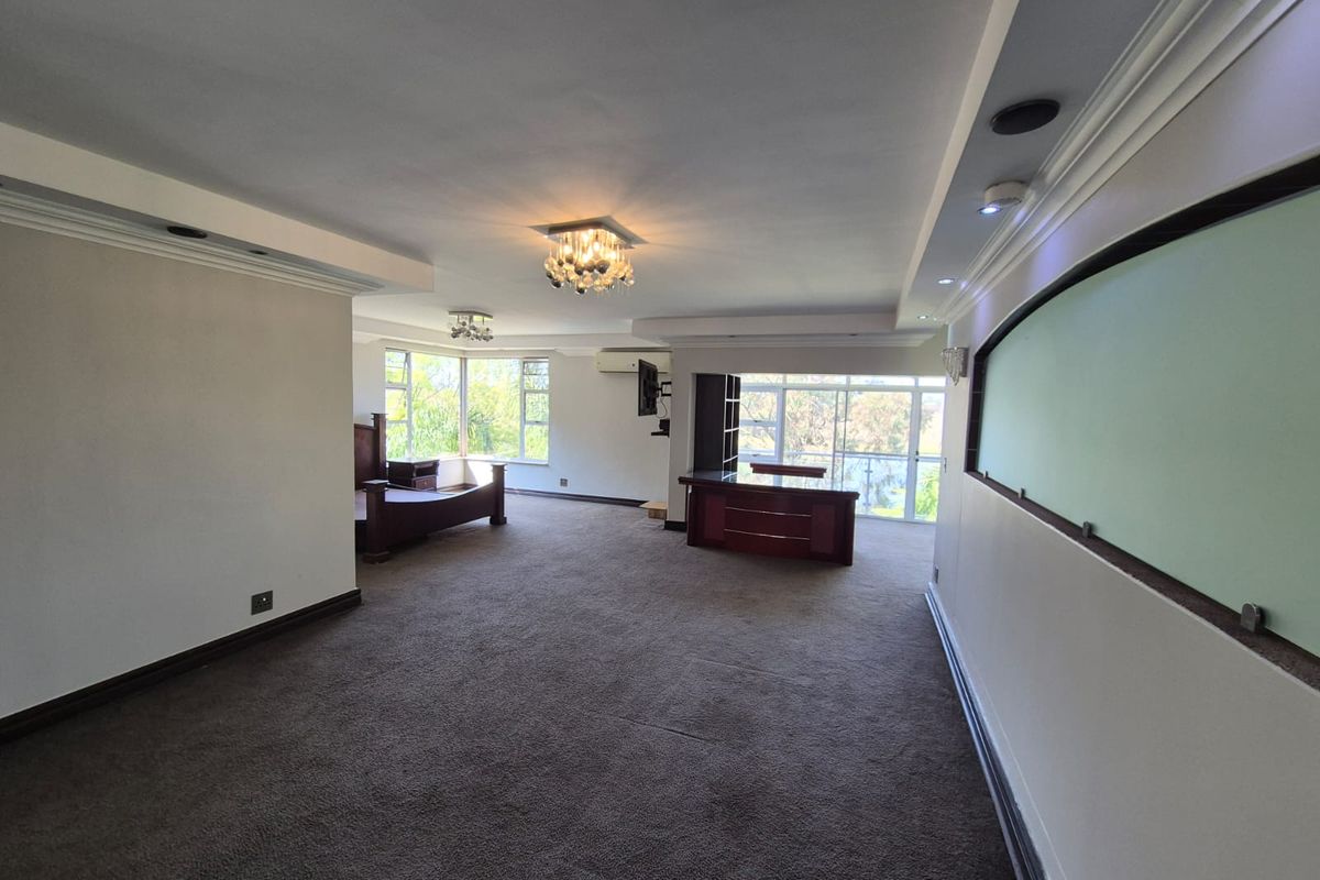 Spacious bedroom featuring recessed lighting, crystal chandeliers, wall-mounted air conditioning, and large sliding glass doors leading to an outdoor area.