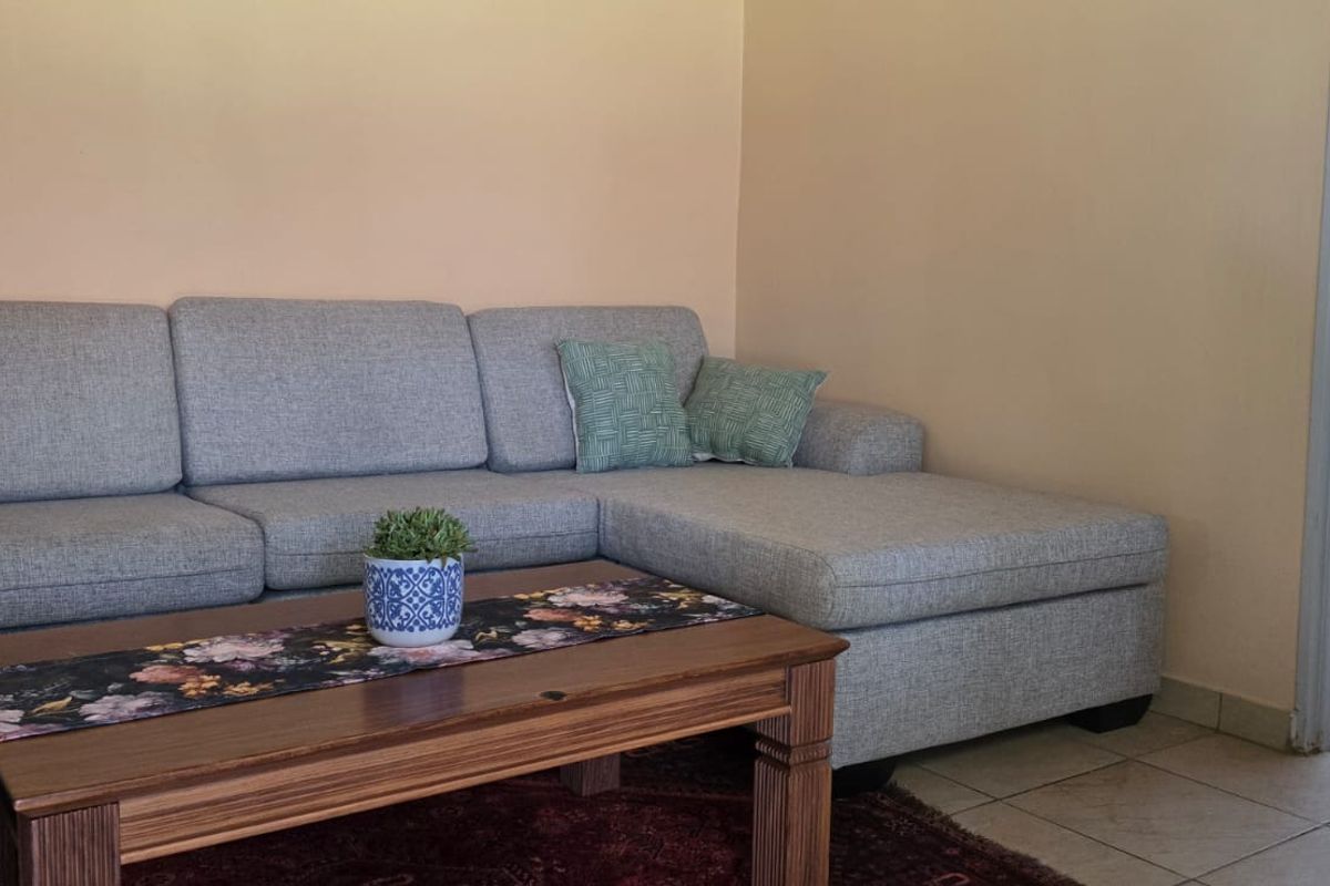 A living room area featuring tiled flooring and neutral wall finishes, with a view into an adjacent bedroom space.