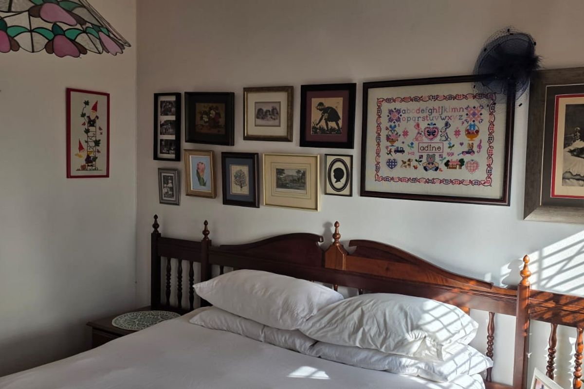 A bedroom featuring a wooden bed frame and natural light filtering through window blinds.