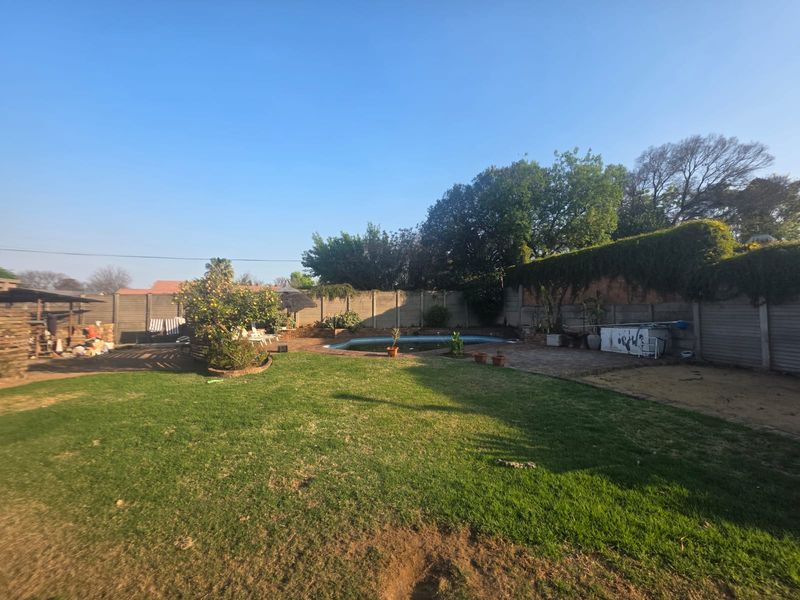 Spacious backyard featuring a swimming pool, paved patio area, and established lawn enclosed by precast concrete boundary walls.