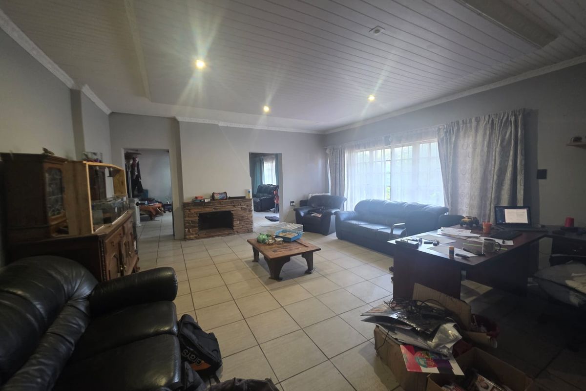 Spacious living room featuring tiled flooring, a stone fireplace, and a timber panelled ceiling with recessed lighting.