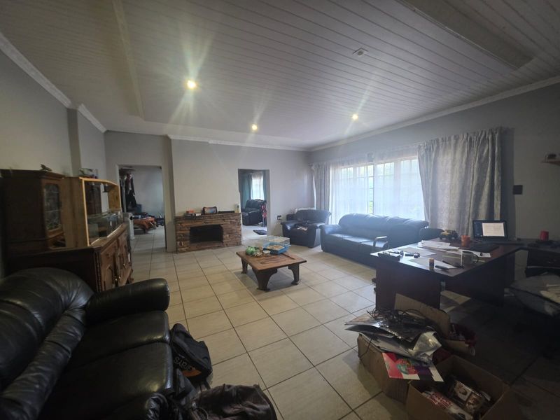 Spacious living room featuring tiled flooring, a stone fireplace, and a timber panelled ceiling with recessed lighting.