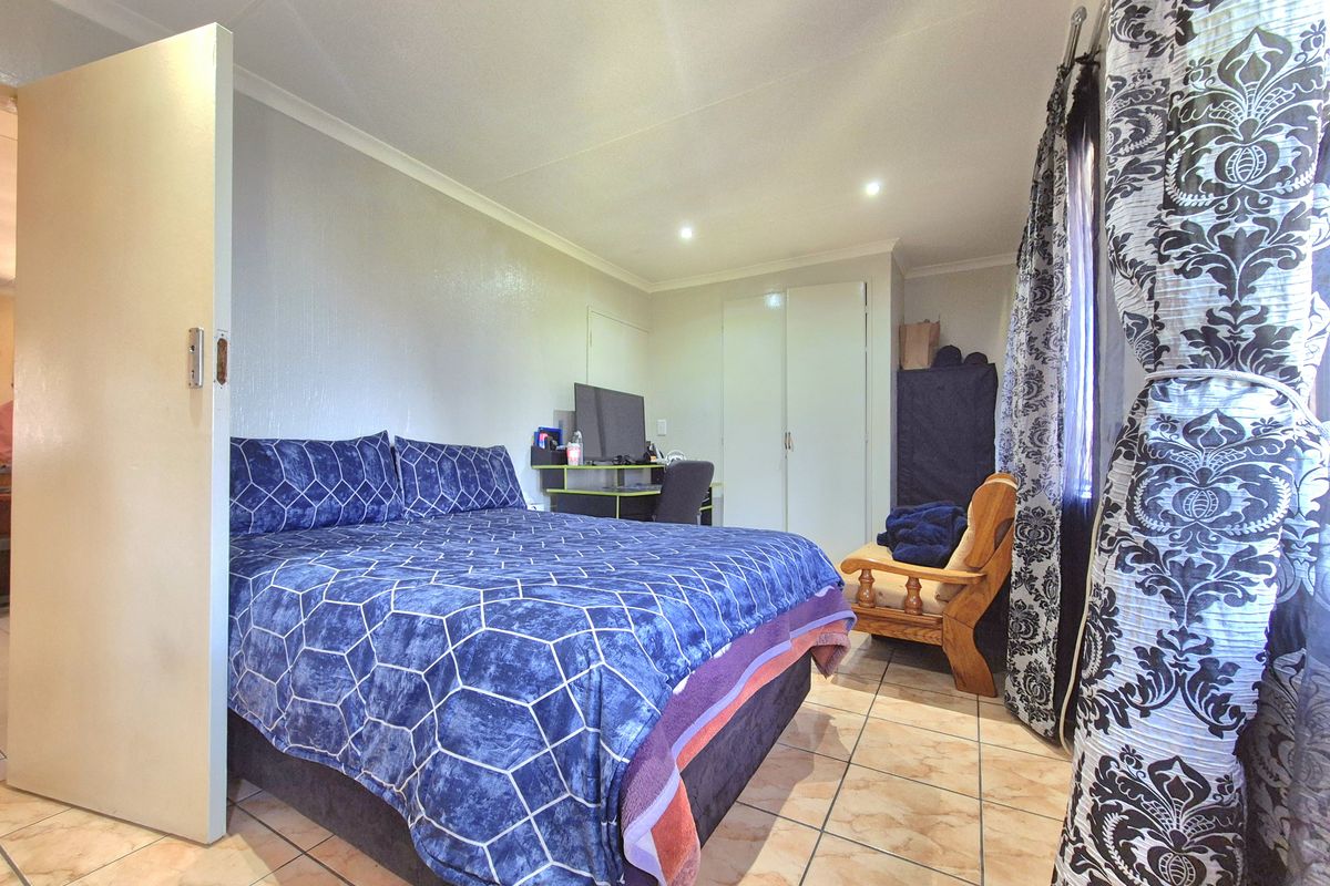 A functional bedroom featuring tiled flooring, built-in cupboards, and recessed downlighting, offering a practical and well-lit living space.