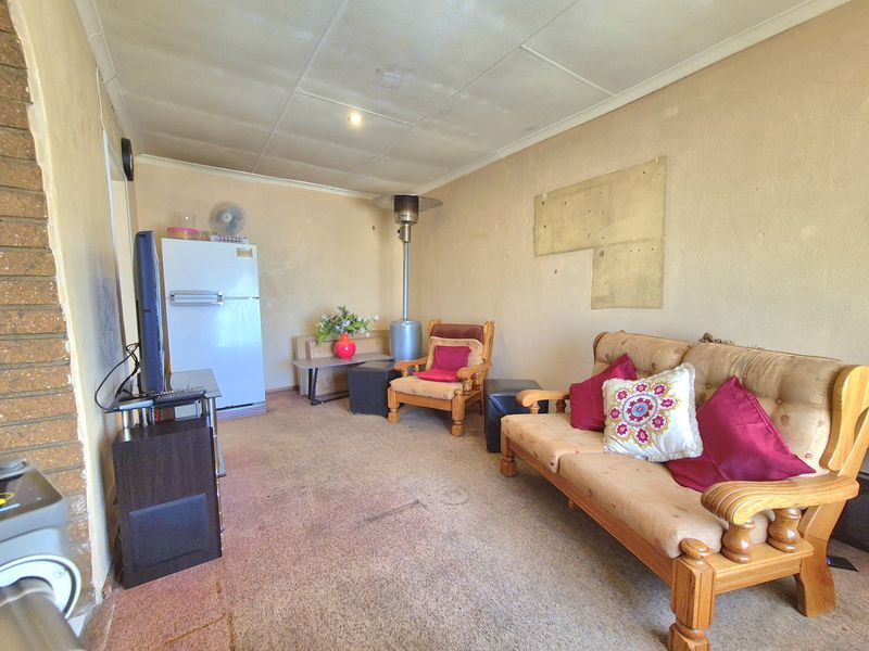 A living room area featuring an exposed brick pillar and tiled ceiling, currently showing signs of wear on the flooring and wall surfaces.