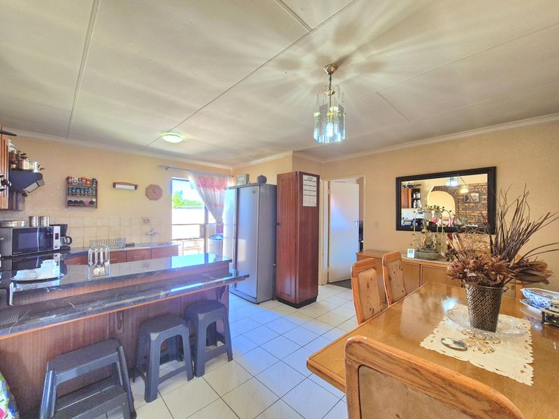 Open plan kitchen and dining area featuring tiled flooring, a breakfast bar, and built-in cabinetry, offering a functional layout for daily living.