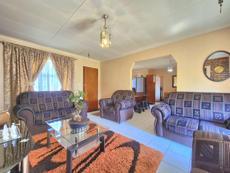 Open plan living area featuring tiled flooring and a classic archway leading to the adjacent space, providing a functional and connected layout.