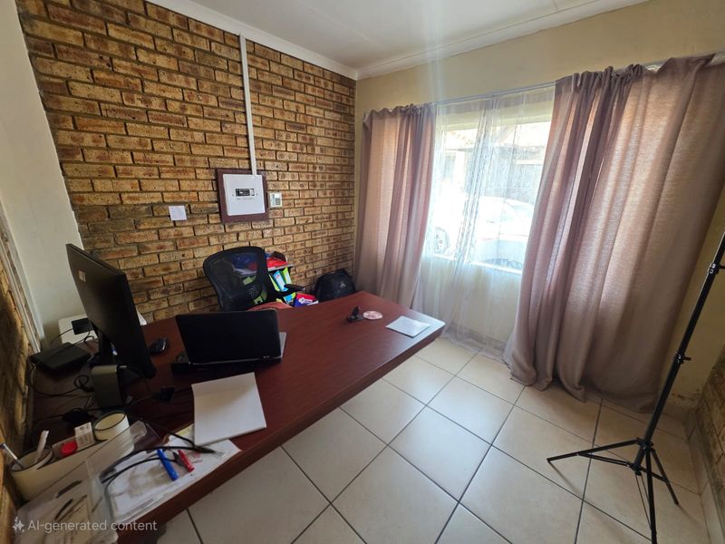 A functional home office space featuring an exposed brick feature wall, ceramic tiled flooring, and natural light from a large window.