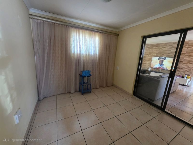An empty living area featuring tiled flooring and a large sliding glass door leading to an adjacent room.