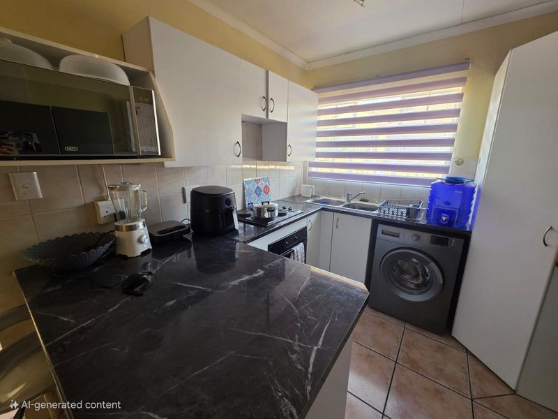 Compact kitchen featuring dark marble-effect countertops, white cabinetry, built-in oven, hob, and tiled flooring with space for a washing machine.