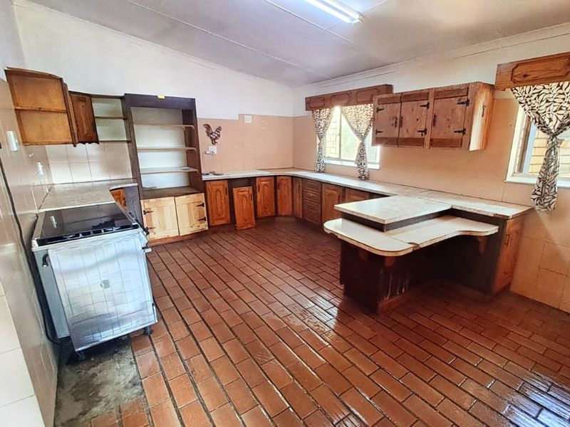 Spacious kitchen featuring extensive wooden cabinetry, tiled flooring, and tiled wall splashbacks, offering a functional layout ready for modern renovation and updates.