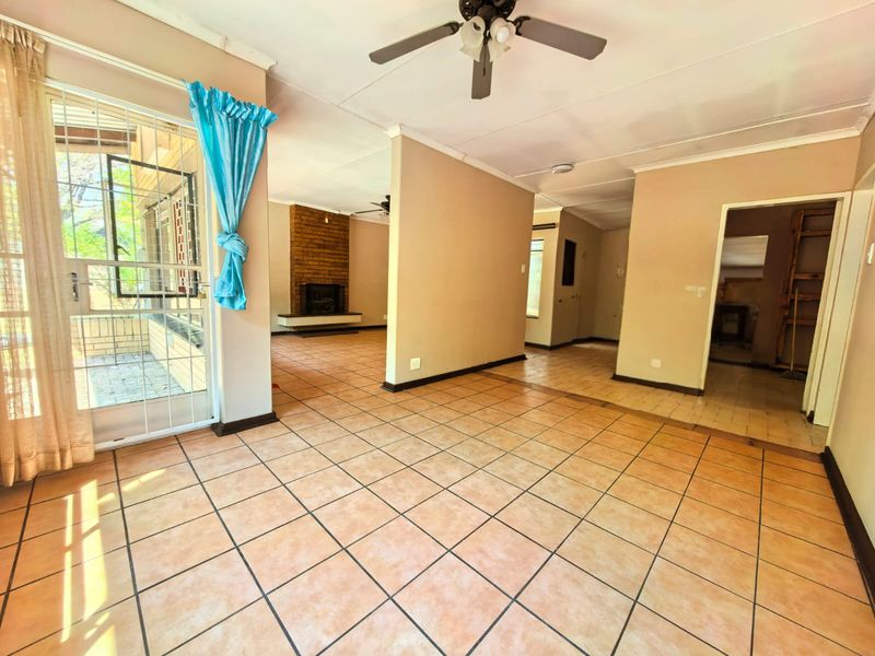 Spacious living area featuring tiled flooring, a brick fireplace, and direct access to an outdoor patio through a sliding glass door.