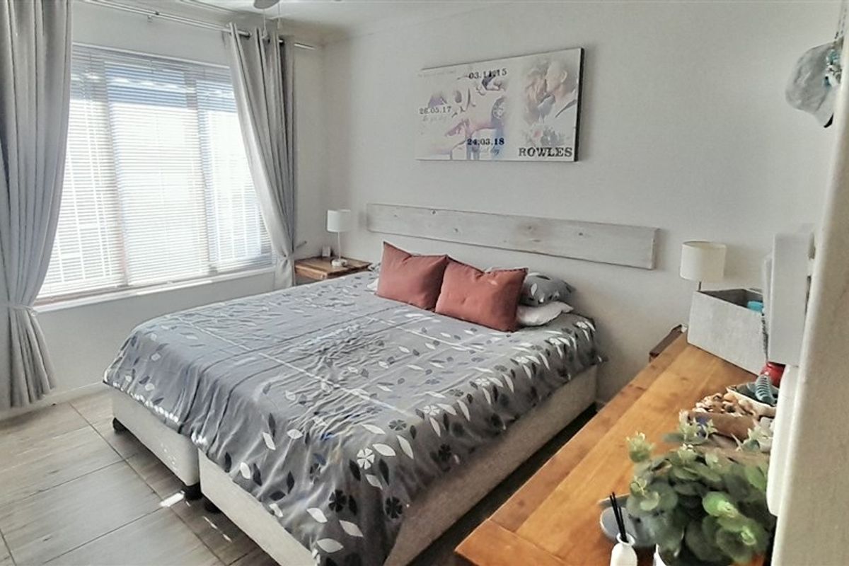 A functional bedroom featuring tiled flooring and large windows with fitted blinds and curtains, providing a neutral space ready for personalization.