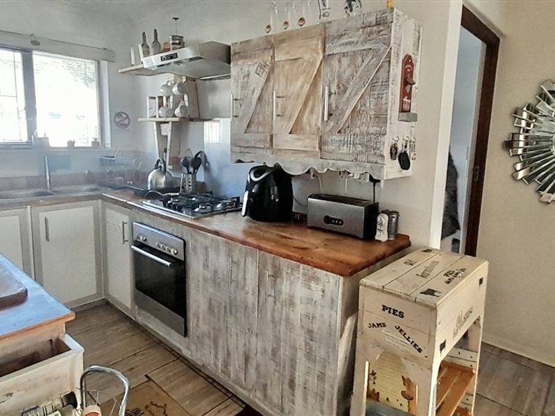 A functional kitchen featuring built-in cabinetry, a gas hob, oven, extractor fan, and wooden countertops, offering a rustic aesthetic with potential for modernization.