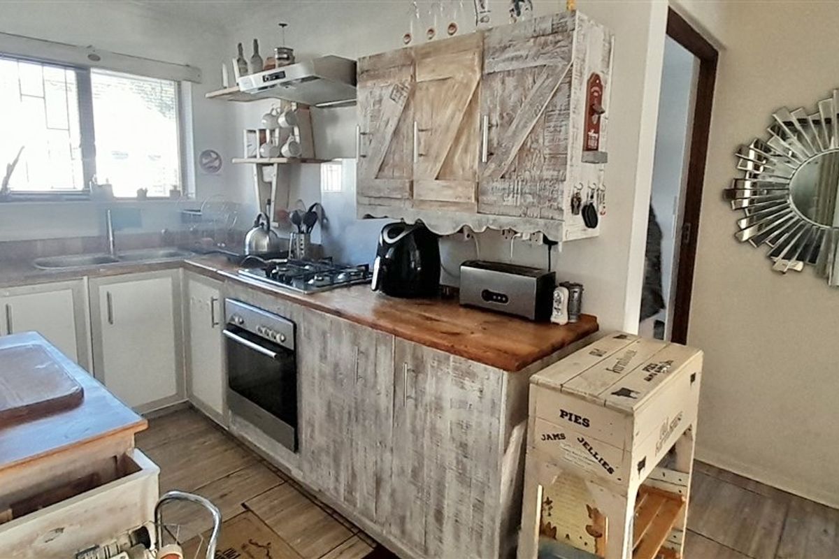 A functional kitchen featuring built-in cabinetry, a gas hob, oven, extractor fan, and wooden countertops, offering a rustic aesthetic with potential for modernization.