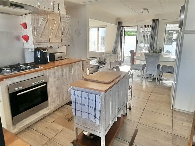 Open-plan kitchen and dining area featuring tiled flooring, built-in oven, gas hob, and direct access to the outdoor patio area.