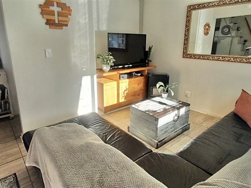An open-plan living area featuring tiled flooring, seamlessly connected to a functional kitchen space with built-in cabinetry and a gas hob.