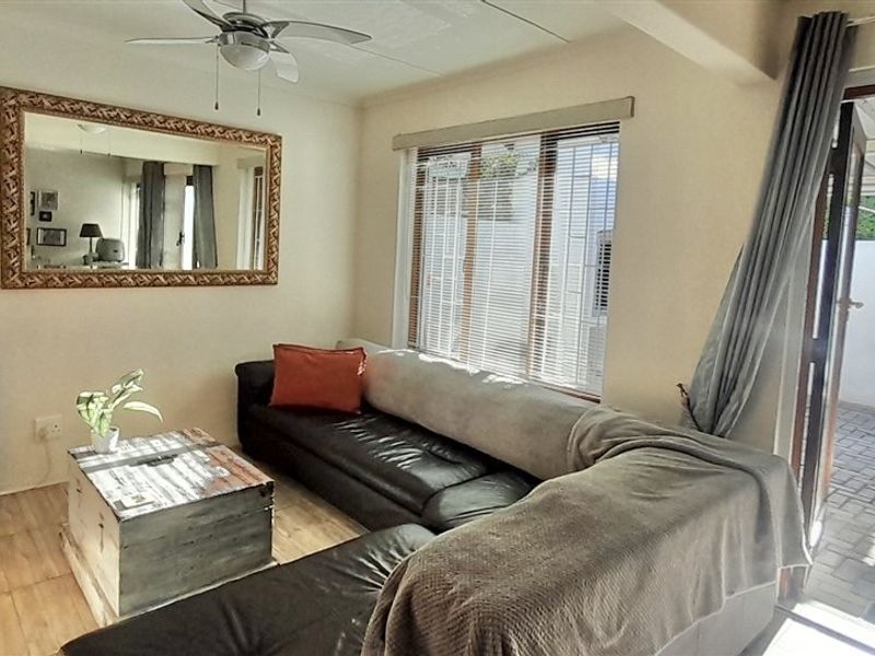 A comfortable living room featuring tiled flooring, a ceiling fan, and direct access to an outdoor patio area through a sliding door.