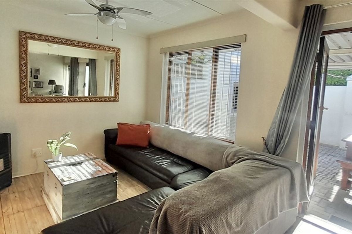 A comfortable living room featuring tiled flooring, a ceiling fan, and direct access to an outdoor patio area through a sliding door.