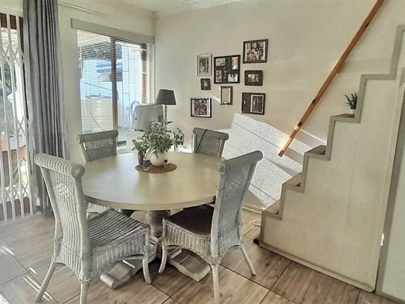 Dining area featuring tiled flooring, built-in under-stair storage, and direct access to the outdoor patio through a sliding security gate.