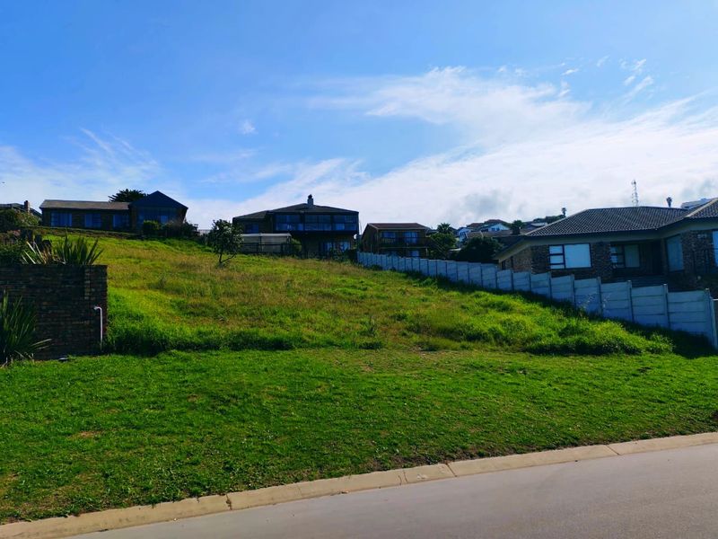 A vacant residential plot featuring a gentle slope, established grass, and existing boundary walling, situated in a developed neighbourhood.