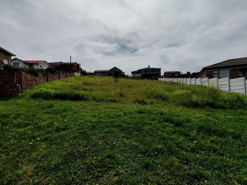 A vacant residential plot featuring a gentle upward slope, enclosed by brick and precast concrete boundary walls in a developed neighbourhood.