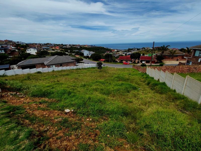 Elevated view of a vacant residential plot featuring boundary walls, overlooking the surrounding neighborhood and distant ocean horizon.