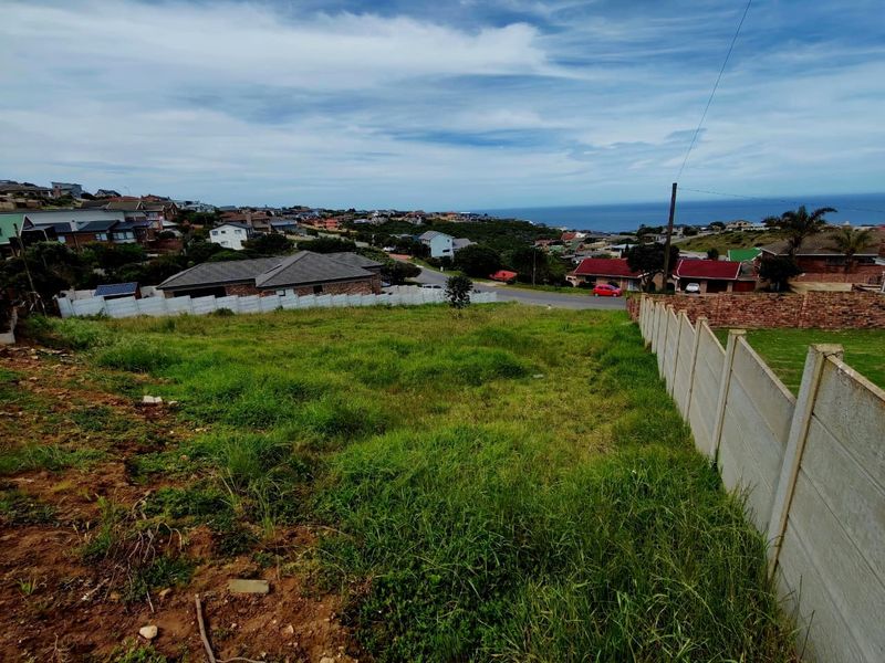 Vacant residential land with a sloped profile, featuring established boundary walls and scenic coastal views in a developed neighborhood.