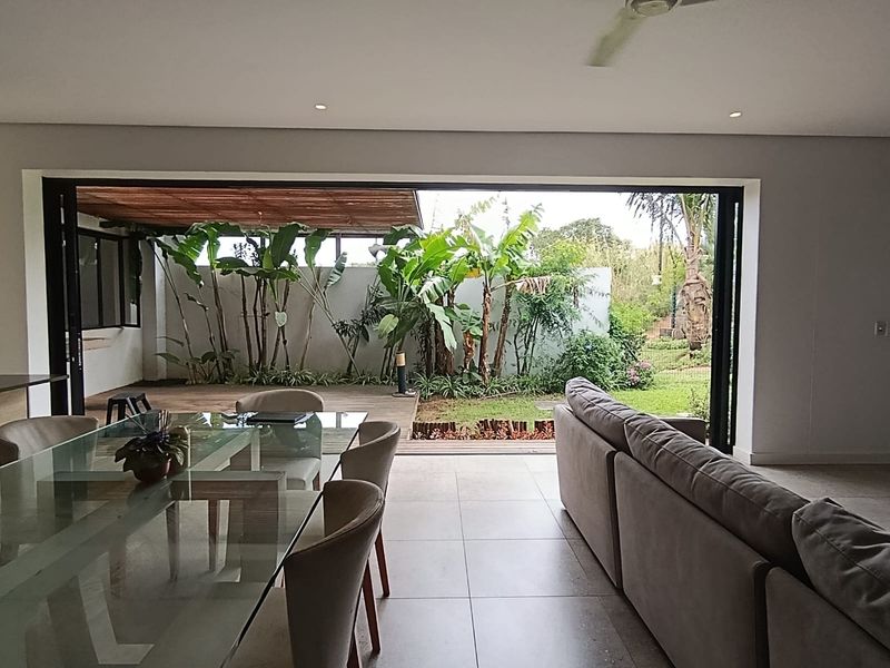 Spacious open-plan living and dining area featuring large sliding glass doors that open onto a wooden deck and private garden.