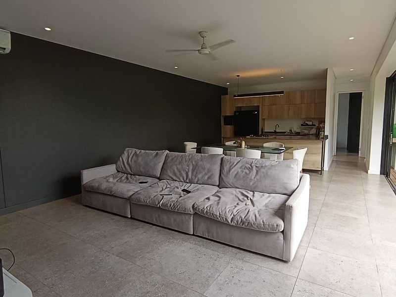 Spacious open-plan living and kitchen area featuring modern tiled flooring, recessed lighting, and direct access to the outdoor space through sliding glass doors.