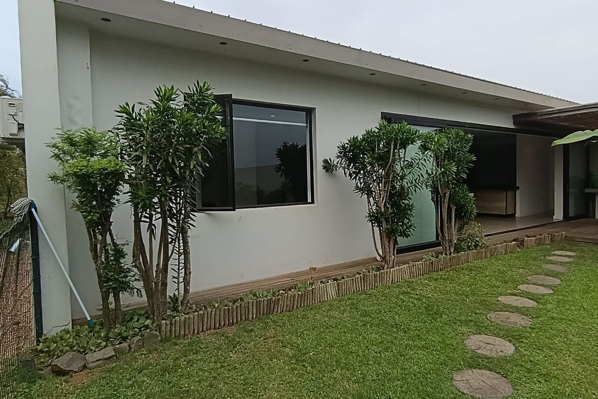 Rear exterior view of the townhouse featuring a timber deck, sliding glass doors, and a well-maintained garden with a stone pathway.