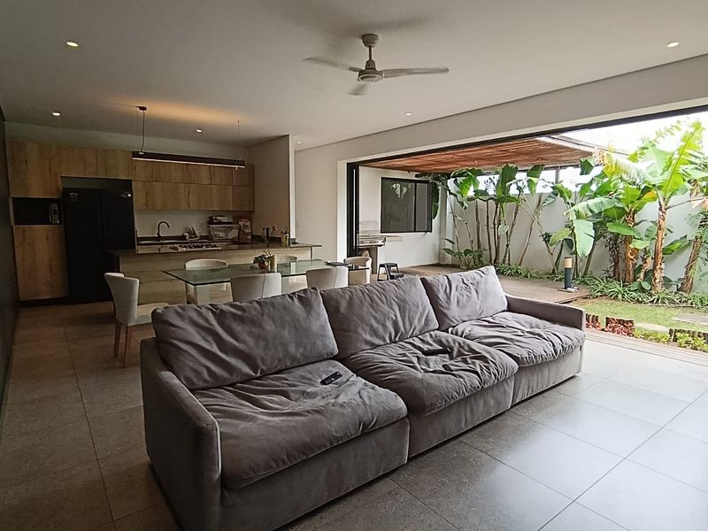 Spacious open-plan living and kitchen area featuring modern cabinetry, tiled floors, and seamless indoor-outdoor flow to a private garden patio.