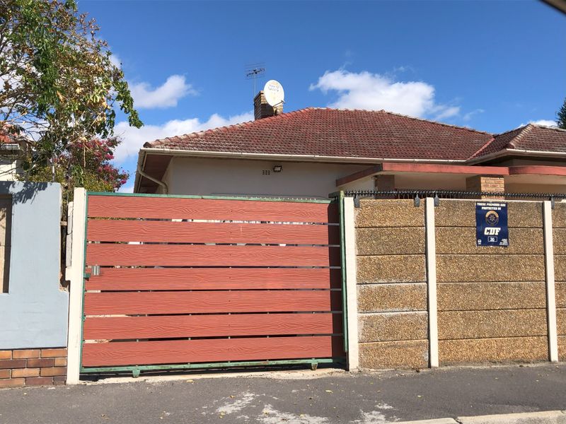 Front exterior view of the cottage featuring a sliding gate, precast concrete boundary wall, and tiled roof with installed satellite dish and antenna.