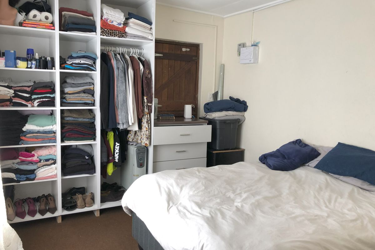 A bedroom featuring built-in shelving units and a traditional timber door, providing functional storage space within the cottage.